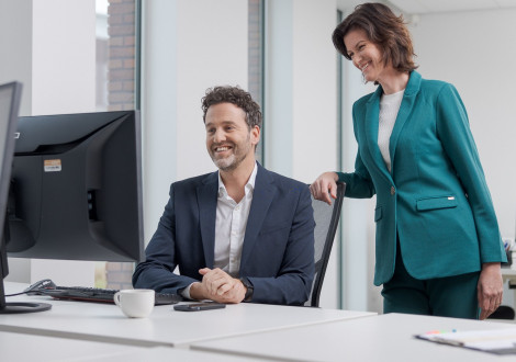 man en vrouw kijken lachend naar computerscherm