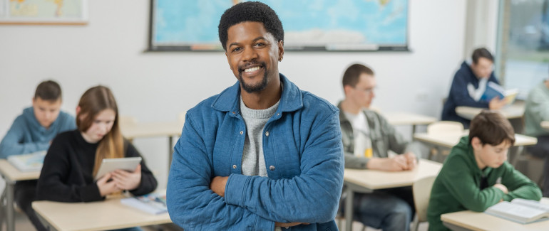 Leraar staat voor de klas, leerlingen zitten op de achtergrond te werken