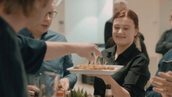 Server biedt hapjes aan op een witte schaal tijdens een sociale bijeenkomst.