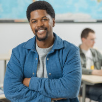 Leraar staat voor de klas, leerlingen zitten op de achtergrond te werken
