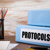 Blauwe mappen met het label "protocols", naast een pot gevuld met kleurpotloden.